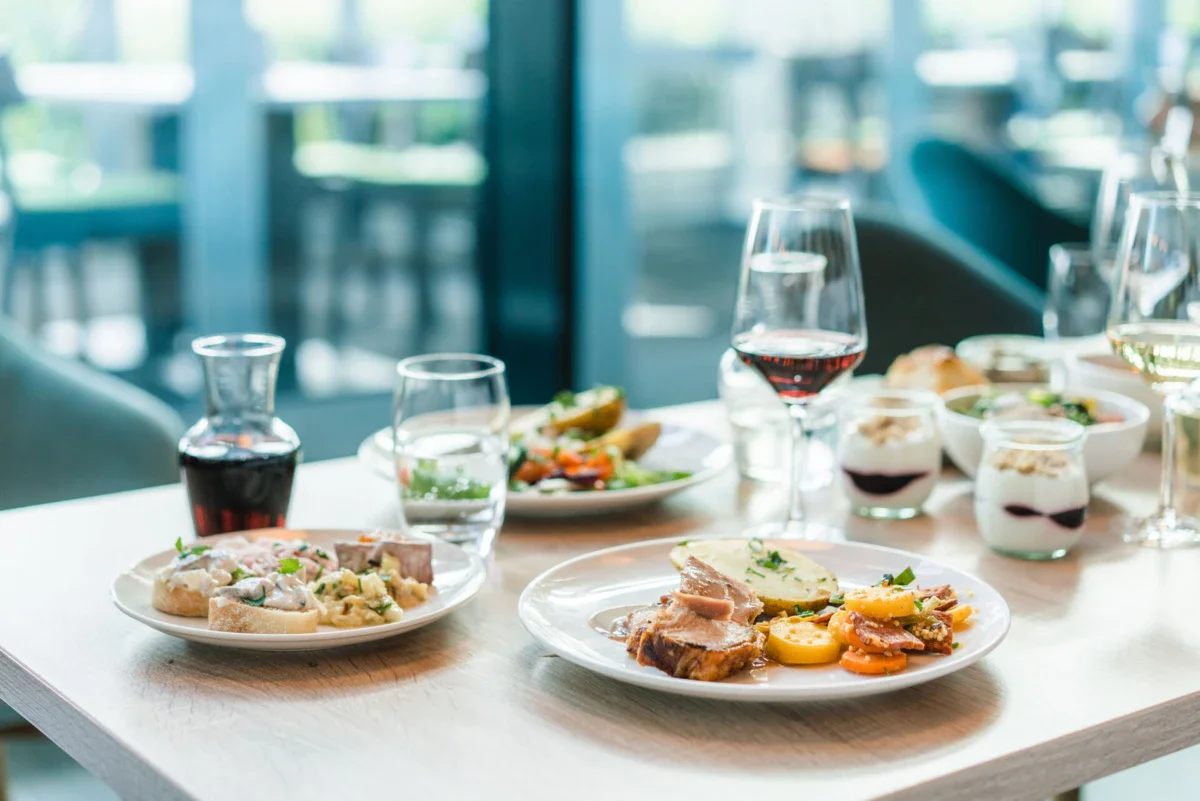 A table with plates full of food and glasses of wine.
