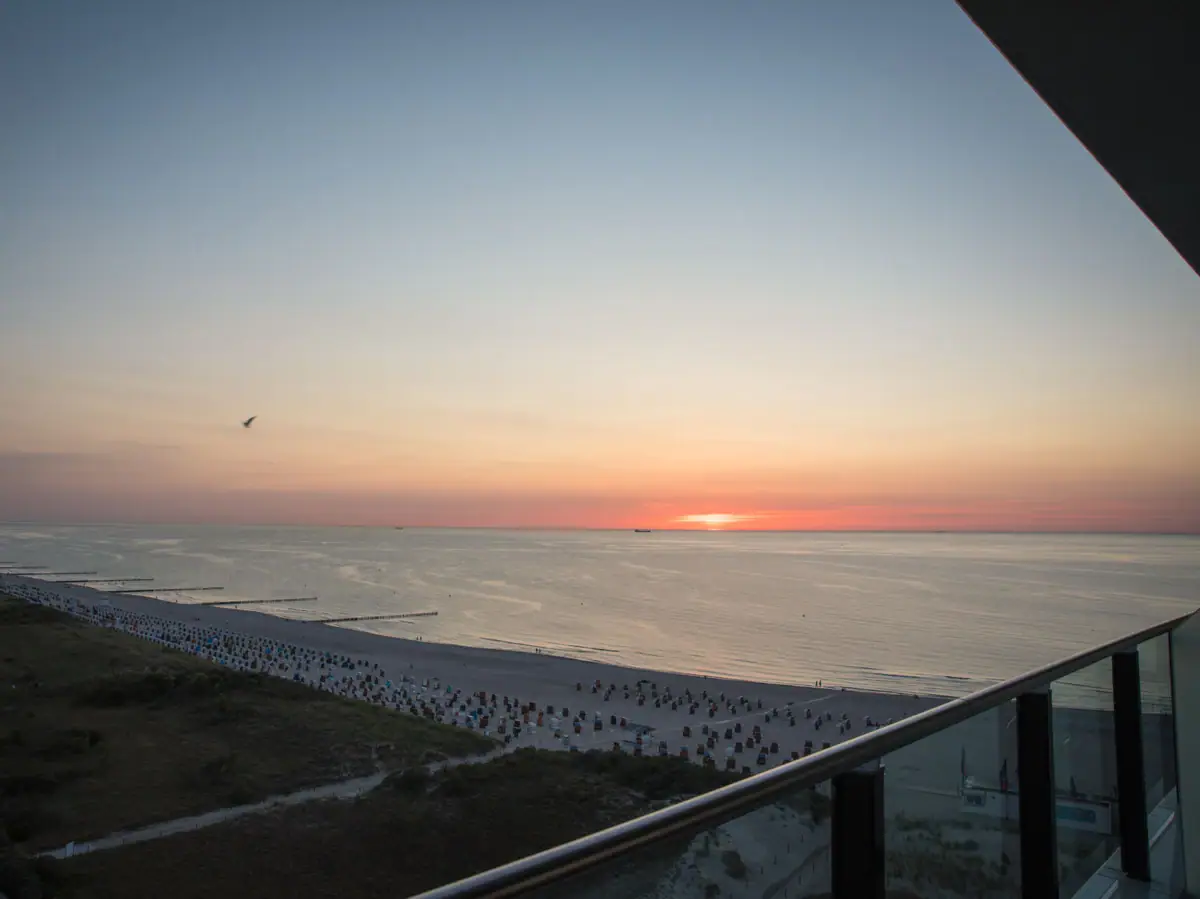 Outlook at aja Warnemünde View of the beach with water and sunset in the background.