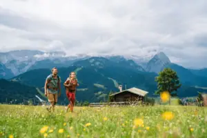 Ein Mann und eine Frau gehen in einem Feld mit Bergen im Hintergrund.