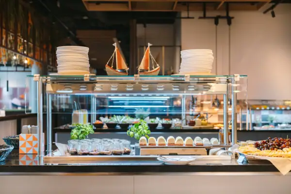 A display of plates and boats on a counter. On the counter are various desserts in glasses and already portioned.