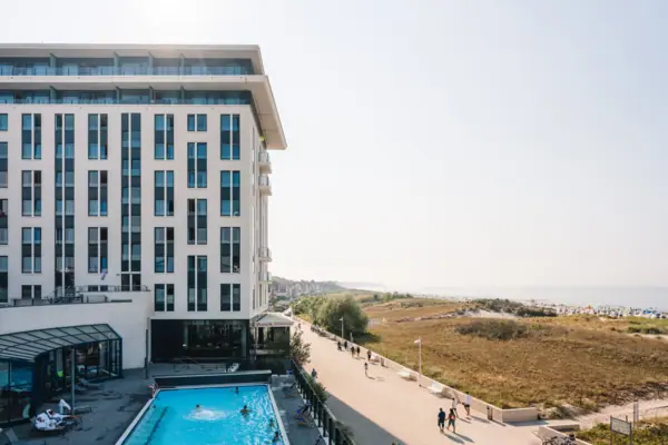 A building with a swimming pool and people walking past.