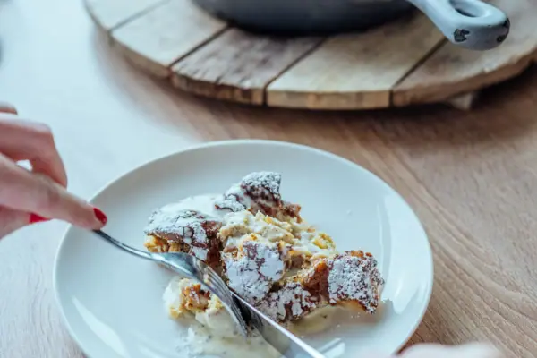 A person is holding a knife and a fork over a plate of food.