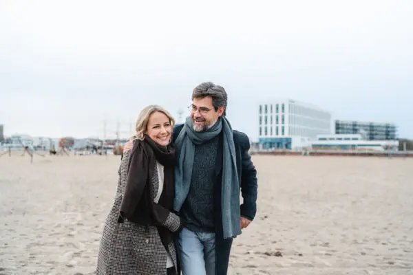 A man and a woman are walking along the beach.