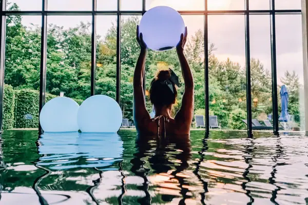 A woman in the pool is holding a ball.