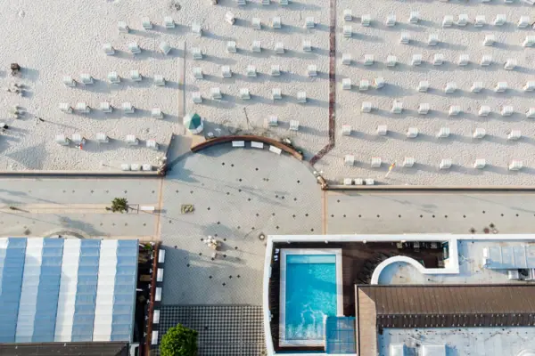 A beach with plenty of sun loungers and an outdoor swimming pool.