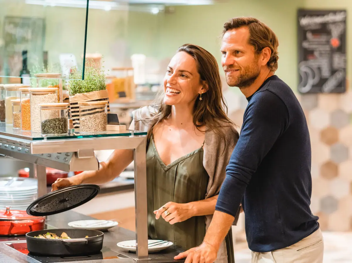 A man and a woman are standing next to a counter with food on it.