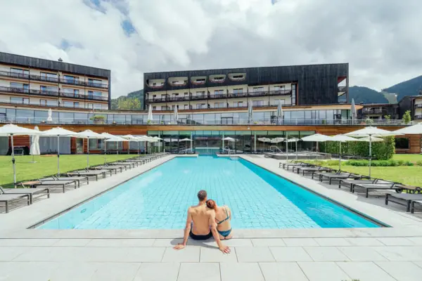 A man and a woman are sitting by a swimming pool.